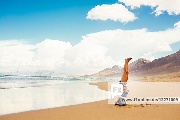 Frau macht Kopfstand am Strand  Corralejo  Fuerteventura  Kanarische Inseln