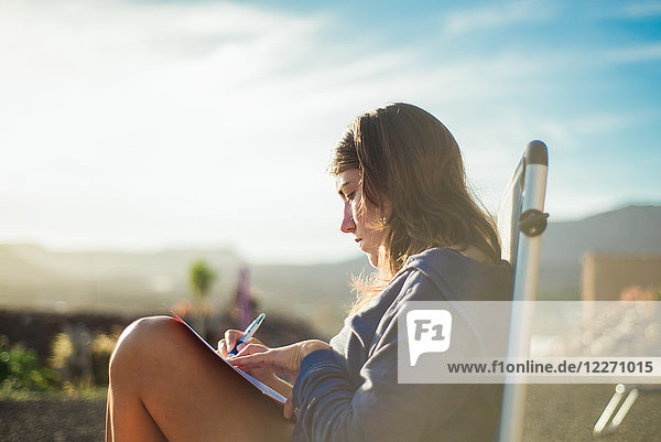 Woman on deckchair writing in journal  Corralejo  Fuerteventura  Canary Islands
