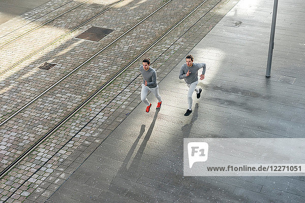 Junge erwachsene männliche Zwillinge  die zusammen laufen  entlang des Bürgersteigs laufen  Hochwinkelansicht