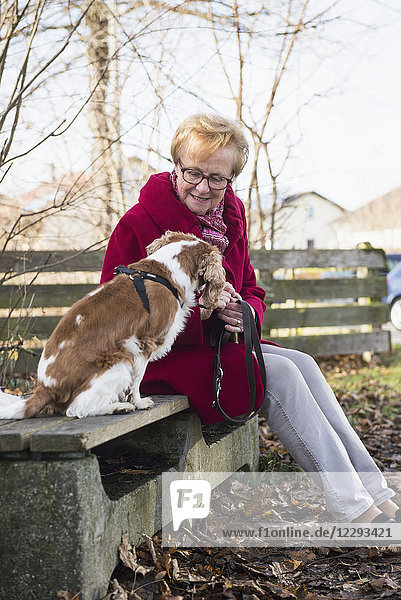 Old woman and her dog sitting outside on bench