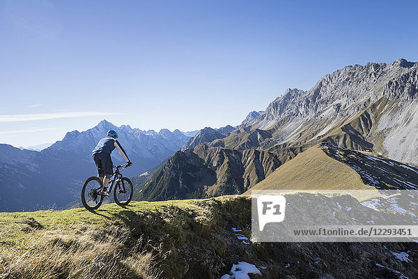 Mountainbiker beim Bergauffahren in alpiner Landschaft