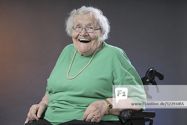 Porträt einer älteren Frau im Rollstuhl sitzend und lachend