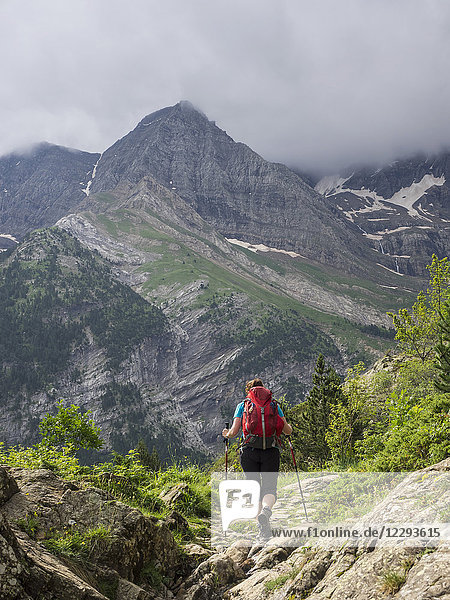 Woman hiking in the High Pyrenees on a single trail with view over Cirque de Gavarnie  France