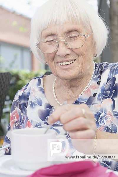 Senior woman stirring tea