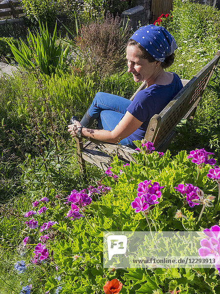 Woman Sitting on wooden bench in garden