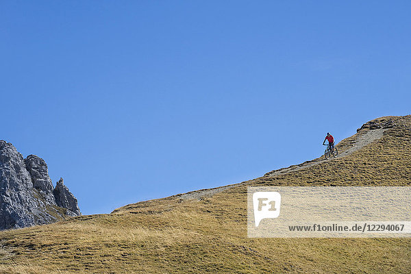 Mountainbiker fährt in alpiner Landschaft bergab