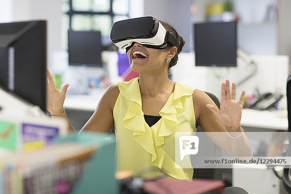 Enthusiastic businesswoman using virtual reality simulator glasses in office