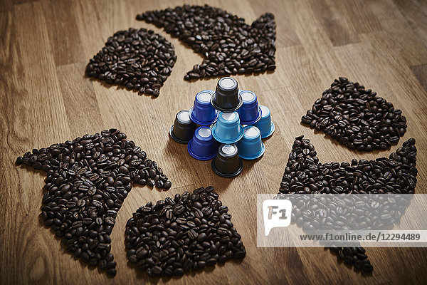 Coffee beans forming recycle symbol around plastic coffee pods