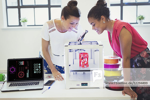 Female designers watching 3D printer in office