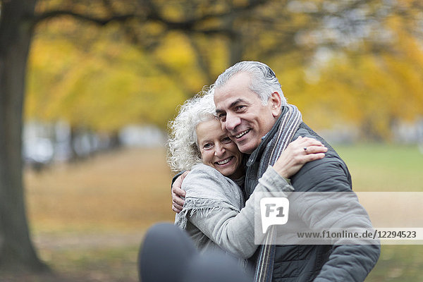 Fröhliches Seniorenpaar beim Umarmen im Herbstpark