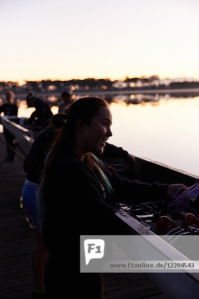 Smiling female rower at scull at sunrise lake