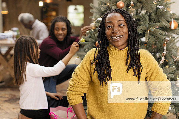 Portrait smiling woman decorating Christmas tree with family