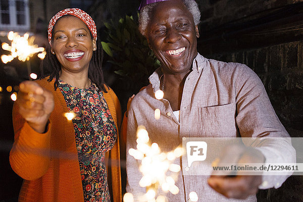 Portrait glücklicher Senior Vater und Tochter beim Feiern mit Wunderkerzen
