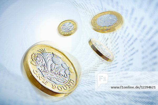 One pound coins surrounded by stock market data