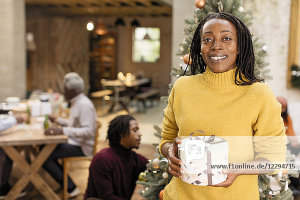 Portrait lächelnde  selbstbewusste Frau mit Weihnachtsgeschenk