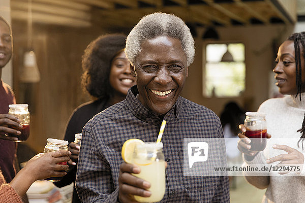 Porträt lächelnder  selbstbewusster Senior  der mit seiner Familie Limonade trinkt.