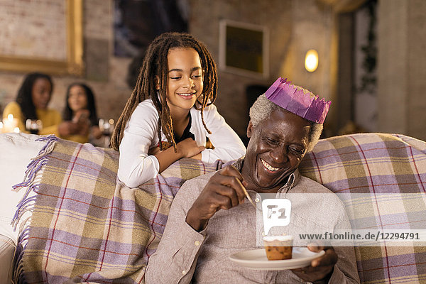 Enkelin beobachtet Großvater in Weihnachtspapier Krone essen Dessert