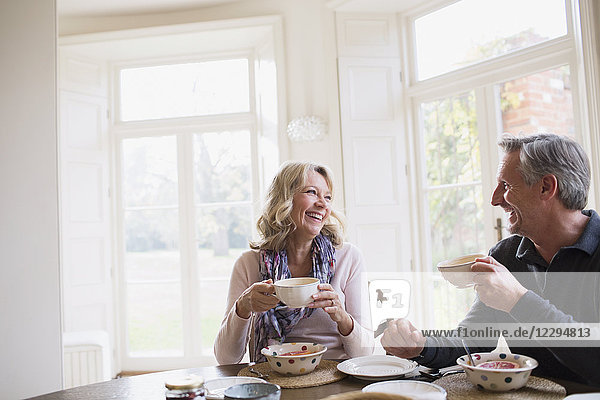 Smiling  happy mature couple eating breakfast  drinking coffee
