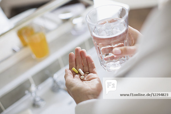 Frau mit Vitaminen und einem Glas Wasser