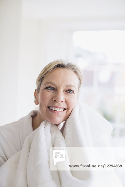 Lächelnde reife Frau trocknet Gesicht mit Handtuch