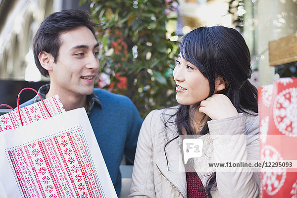 Loving young couple with shopping bags looking at each other outdoors