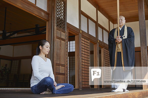 Japanischer Priester predigt zu einer Frau in einem Tempel
