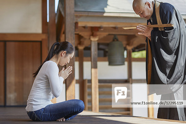 Japanischer Priester predigt zu einer Frau in einem Tempel