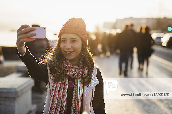 Smiling mid adult woman taking selfie from smart phone during sunset