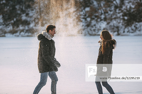 Side view of playful man and woman enjoying in snow