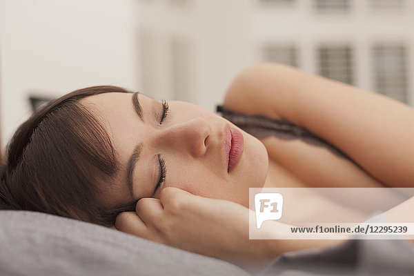 Close-up of beautiful young woman sleeping on bed at home