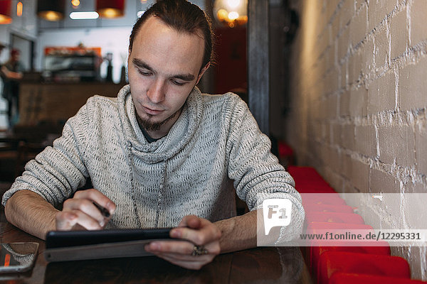 Young man using digital tablet at cafe