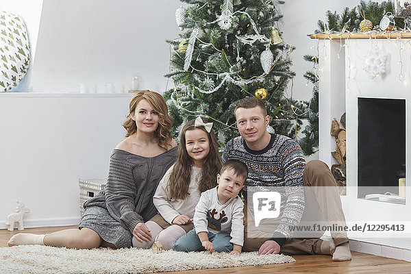 Portrait of happy family sitting against Christmas tree