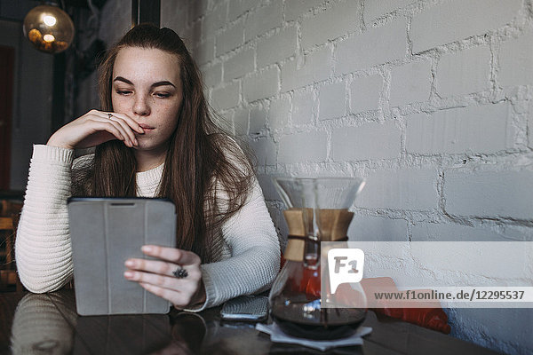 Young woman using digital tablet at cafe
