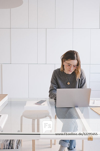 Young female entrepreneur using laptop at desk in design studio