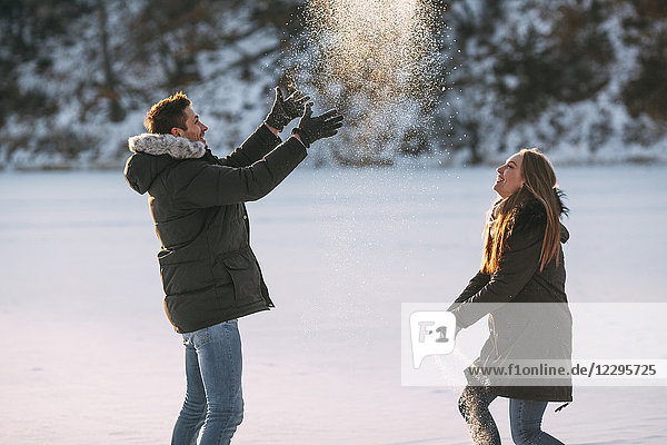 Seitenansicht des verspielten Paares bei Schneefall