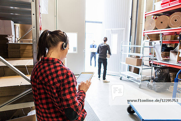 Female using digital tablet while male workers standing at doorway
