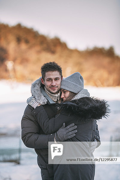 Portrait of smiling man embracing woman during winter