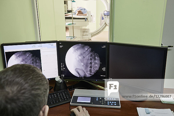 Hochwinkelansicht des Arztes beim Betrachten von medizinischen Röntgenbildern am Computer im Krankenhaus
