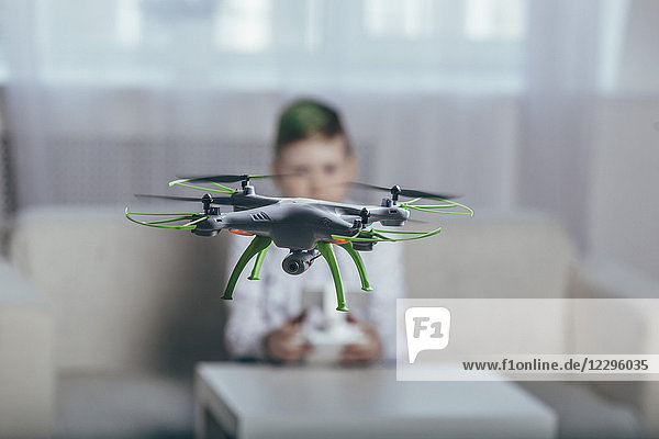 Junge fliegende Drohne im Wohnzimmer zu Hause