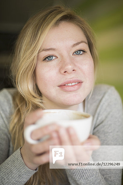 Portrait of young woman holding coffee cup at home