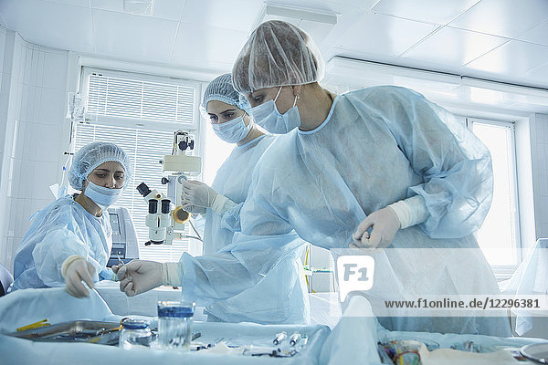 Chirurgin  die während der Operation im Krankenhaus medizinische Geräte an den Arzt weitergibt.