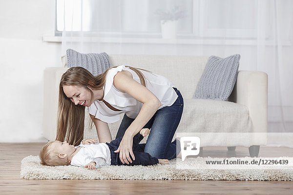 Verspielte Mutter und Tochter auf dem Teppich zu Hause