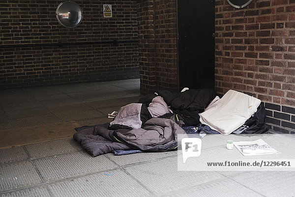 Hochwinkelansicht des Schlafsacks auf dem Fußweg durch die Ziegelmauer in der Stadt