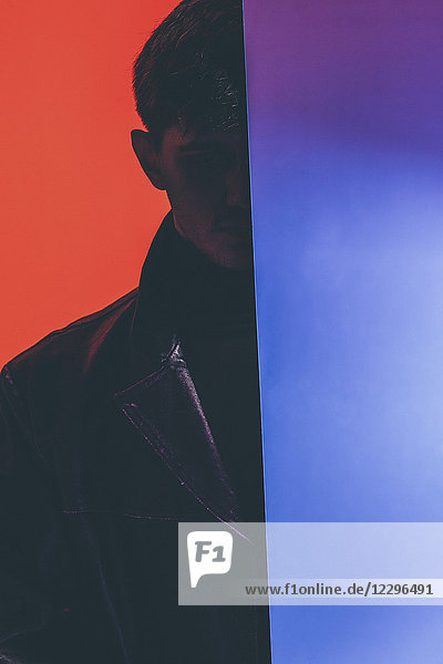 Young fashion model standing by mirror against orange background