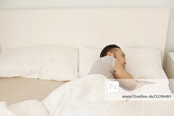 Hochwinkelansicht eines jungen Mannes  der zu Hause im Bett schläft.