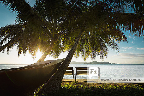 Boot und Bänke am Strand bei Sonnenuntergang  Insel La Digue  Seychellen