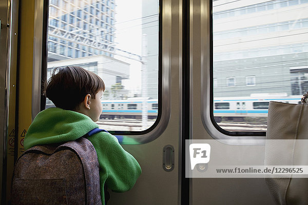 Rückansicht des Jungen  der durch die geschlossene Tür schaut  während er im Zug fährt
