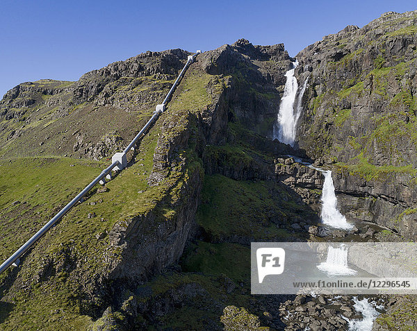 Scenic view of waterfall by water pipeline on mountain  Iceland