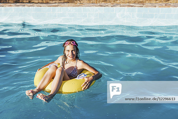 Full length portrait of happy girl in inflatable ring on swimming pool