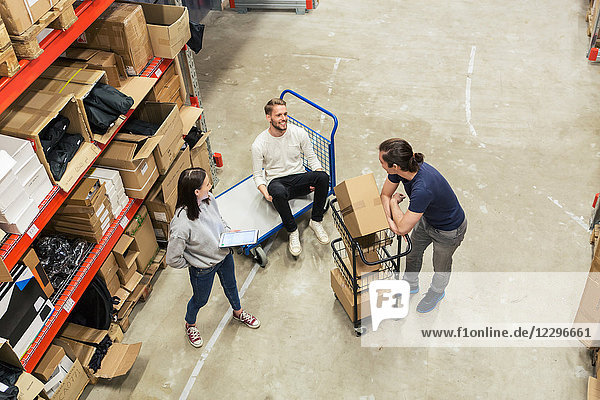 High angle view of male and female coworkers talking in distribution house